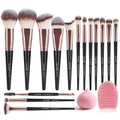 Set of makeup brushes with black handles and rose gold ferrules, accompanied by a pink sponge and puff on a white background.