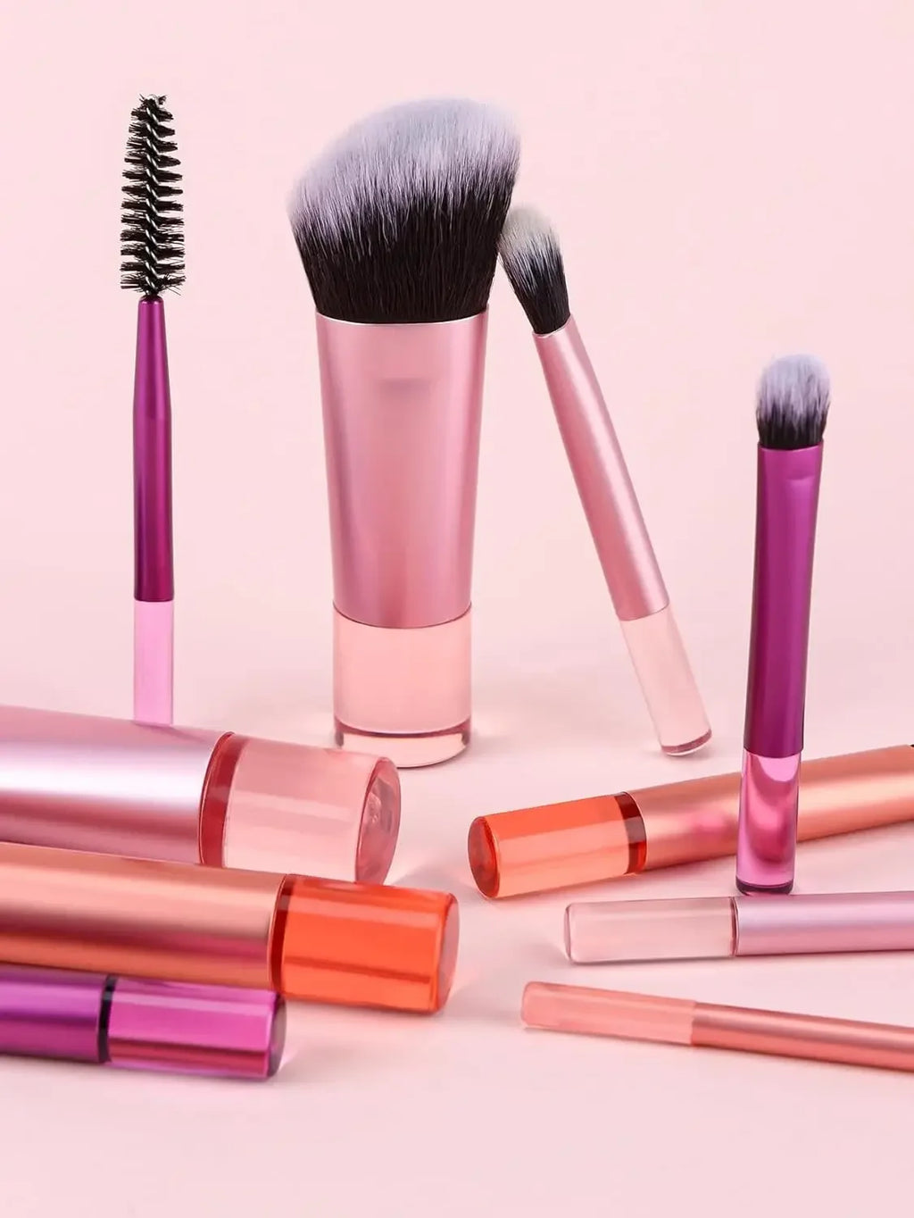 Makeup brushes with pink and purple handles on a light pink background
