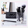 Makeup brushes in a clear holder with a black pouch labeled 'JESSUP' on a white surface.