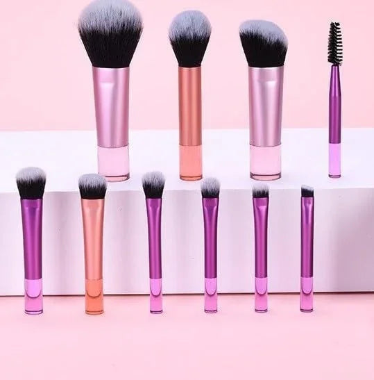 Set of makeup brushes with pink and rose gold handles on a pink background