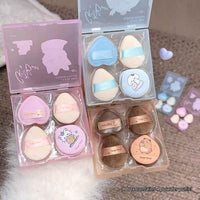 Set of cute powder puff containers with cartoon designs on a textured surface.