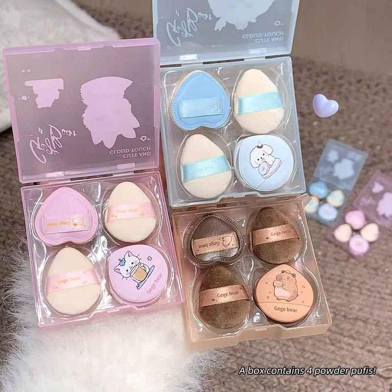 Set of cute powder puff containers with cartoon designs on a textured surface.