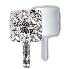 Handheld mirror with decorative handle and 'Gege Bear' text on a white background