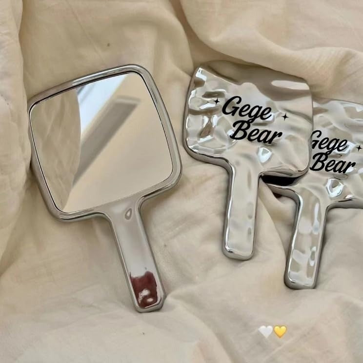Two handheld mirrors with 'Gege Bear' branding on a beige fabric background