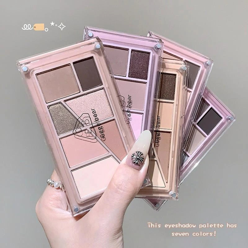 Makeup eyeshadow palette held by a hand with a gray background