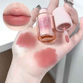 Hand holding a lip gloss with swatches on the skin and close-up of lips.