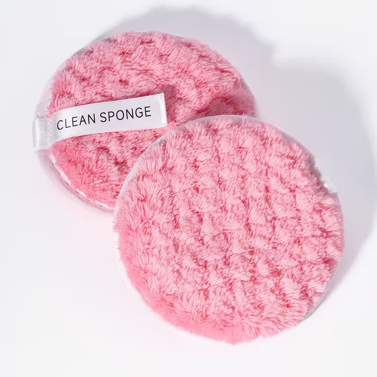 2 baby pink makeup remover pads on a white background 