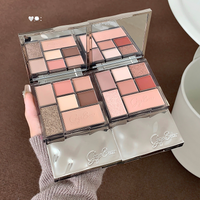 a hand holding 2 eyeshadow palettes on her hand against the grey carpet