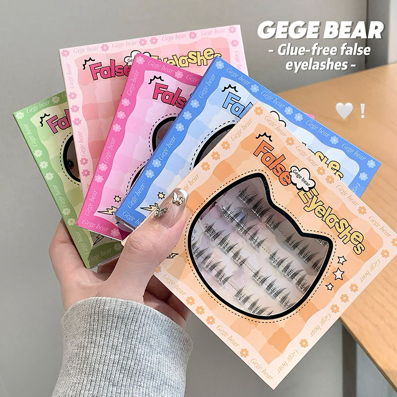 Hand holding a set of false eyelashes packaging with colorful designs.