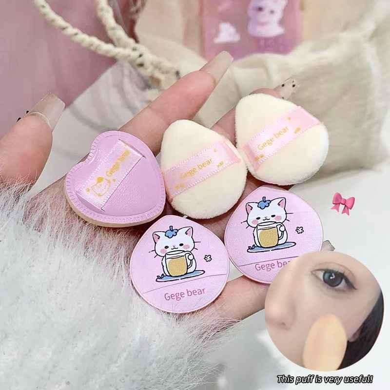 Set of small round makeup puffs with cartoon designs on a fluffy white surface.