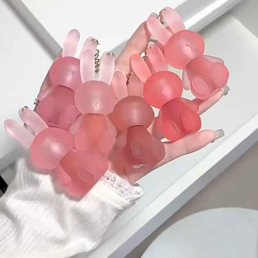 pink bunny keychain lipstick on a hand with white background 