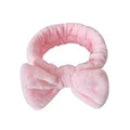 Pink plush bow headband on a white background