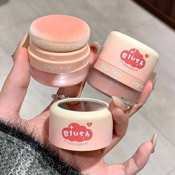 Three pink gege bear blush products with 'Gege bear' branding held in a hand.