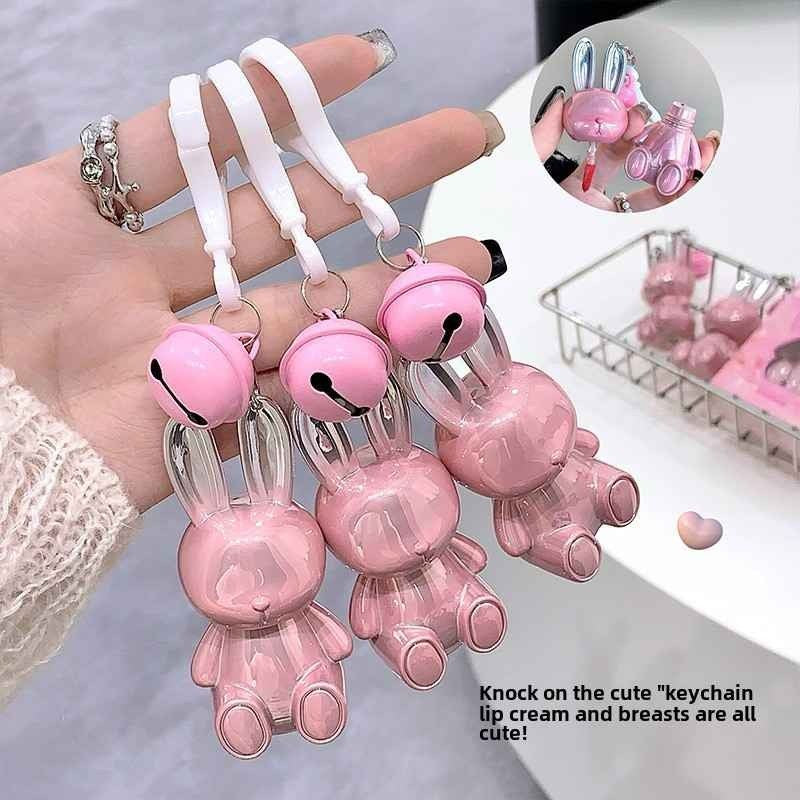 Pink bunny-shaped keychain lip stick held by a hand with a blurred background