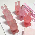 Pink rabbit-shaped lipsticks on a white surface