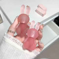 Pink rabbit-shaped keychain lipstick held by a hand with white lace sleeves.