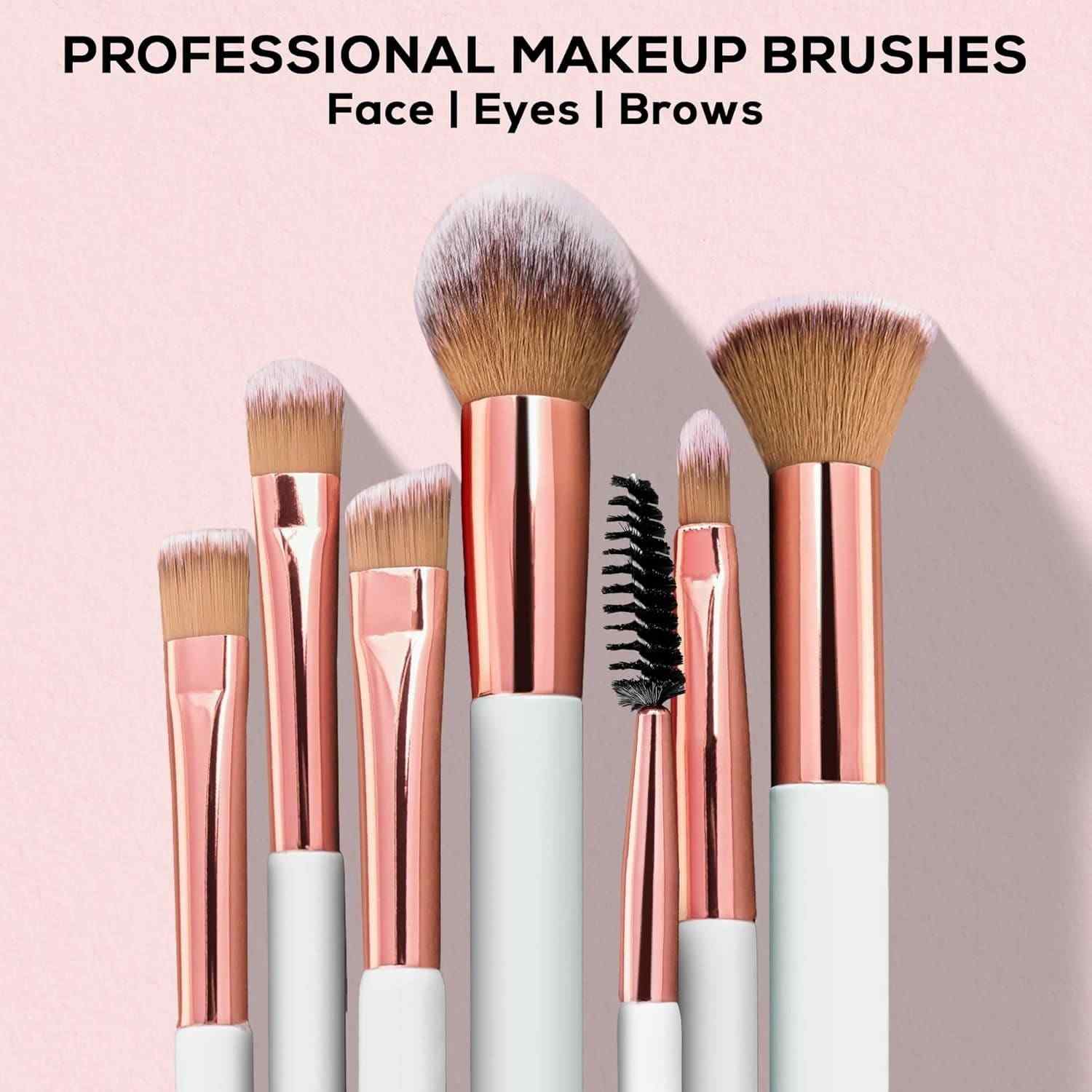 Set of professional makeup brushes with rose gold and white handles on a pink background.